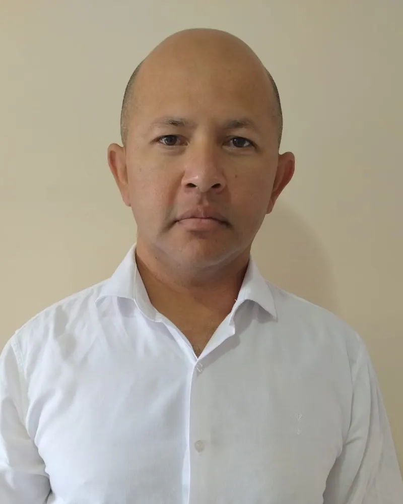 Dr. Ednelson Farias, retrato frontal de camisa branca em fundo bege claro