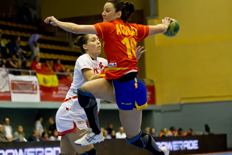 Jogadora de handebol saltando com o braço armado para o arremesso